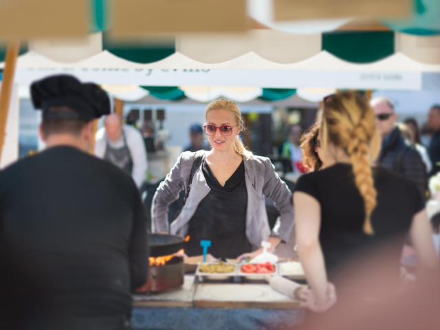 A woman getting food from a vendor at a Bacon Festival