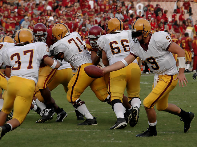 A college running back takes a handoff behind the line of scrimmage