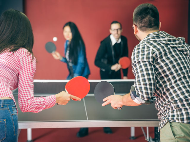 A person about to serve in a doubles Table Tennis match.