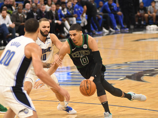 Jayson Tatum dribbling past two Orland Magic players